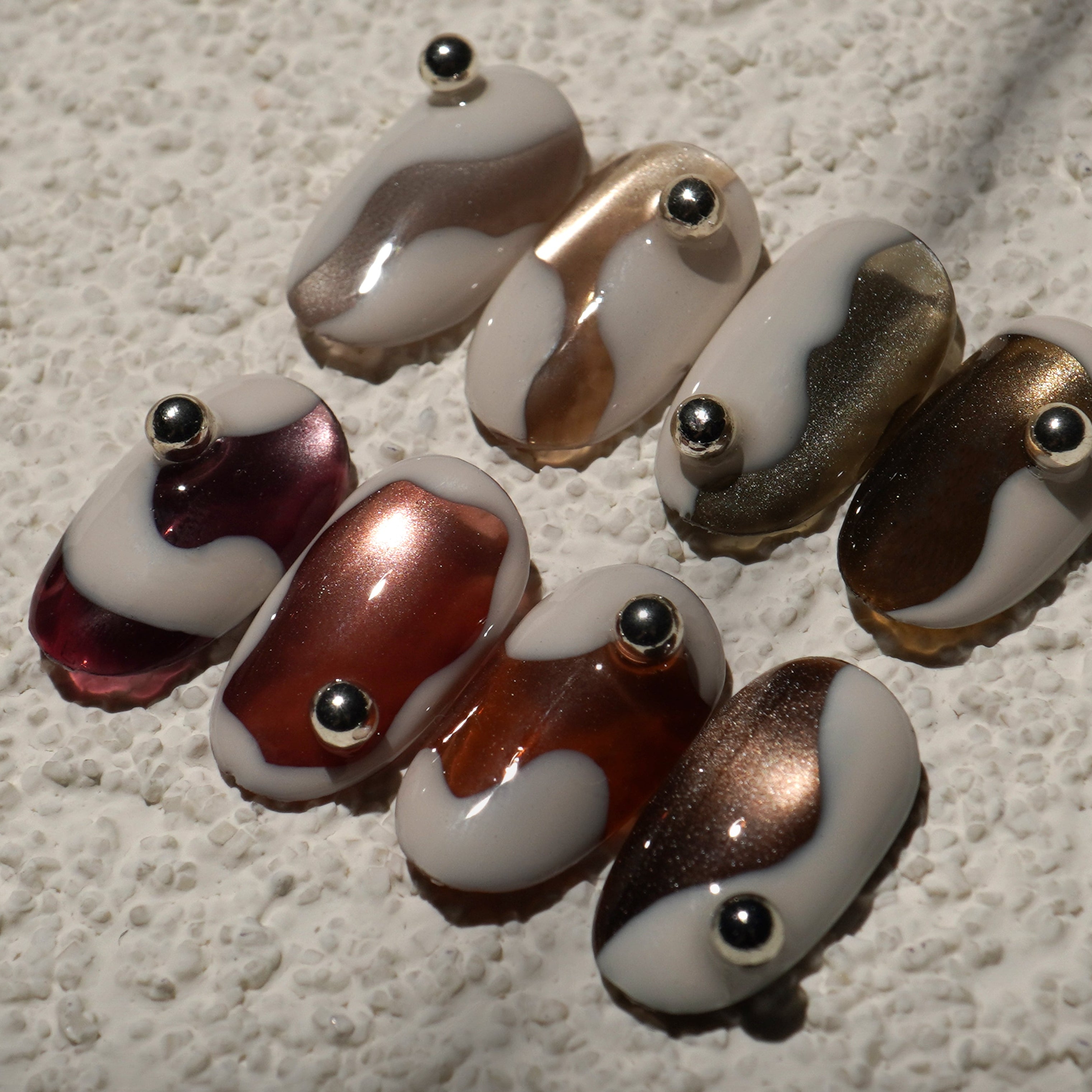 Set of glass beads with brown and white patterns on a textured surface